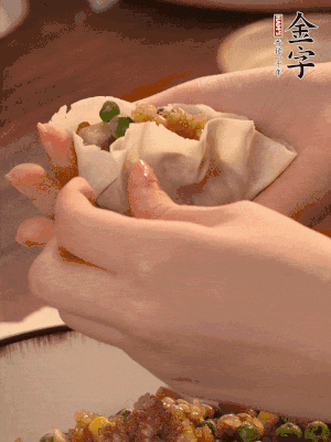 取一大勺餡料放進(jìn)餃子皮里，用大拇指按住頂部餡料，再用虎口掐出形狀。