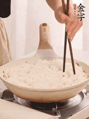 把瀝干水分的米飯均勻鋪在上面，筷子戳幾個(gè)洞，以便透氣，轉(zhuǎn)小火蓋上蓋子燜至水分收干，大概10分鐘。